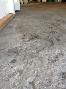 Before: Garage showing significant damage to floor